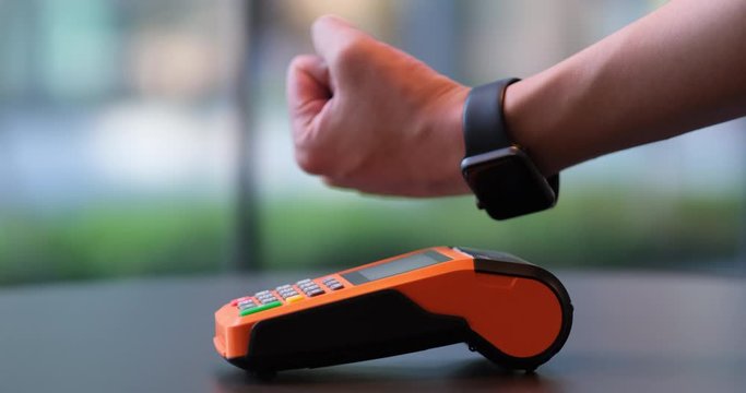 close up people using smart watch to pay over pos terminal on table.