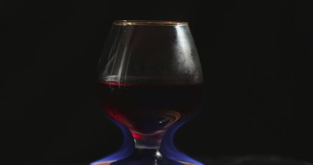 A glass of red wine on fire stands on a beautiful natural stone