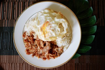Close-up of fried pork with garlic pepper with fried egg top on rice and the plate.