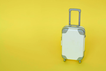 white toy suitcase on a yellow background. the concept of travel. space for text