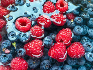 Colorful, juicy background from blackberries and raspberries submerged in water. Healthy food concept.