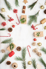 Festive background of gift boxes, cinnamon sticks, decorative berries, christmas tree branches on white wooden table, copy space in the middle, on white table, selective focus