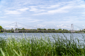 Suspension bridge in the morning which has blur grasses in foreground