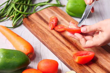 Hand Of Person Cutting Tomatoes On Chopping Board 