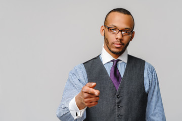 Handsome American-African man pointing you while standing against grey background