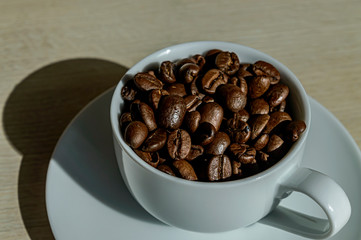 white cup with arabica coffee beans close up