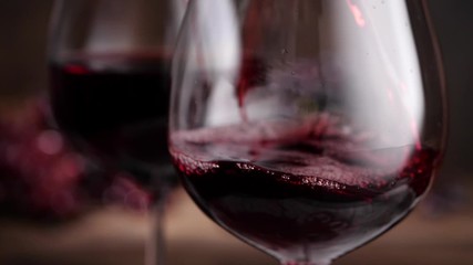 Closeup trickle of red wine pouring into wineglass in slow motion during festive event
