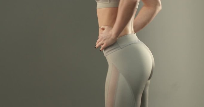 Close-up of sportswoman torso and lower body in sports leggings, woman workout, turning sideways to show booty and thigh exercises progress, show-off buttocks with strong gluteus
