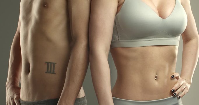 Close-up of male and female sportsmen bodies, two athletes chest with abodminal abs, sportsman and sportswoman showing muscles, tense stomach, inhale and exhale, workout and fitness concept