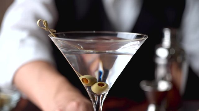 bartender serving martini in glass at bar