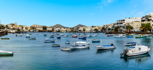 Fototapeta na wymiar A panorama view of the idyllic scene of small boats moored in the lagoon of Charco de San Gines in Arrecife, Lanzarote on a bright sunny afternoon