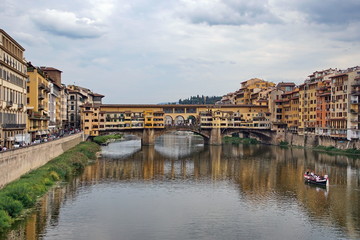The Arno river with the famous Ponte Vecchio (Old Bridge), a medieval stone arch bridge with shops built along it, in Florence, Italy