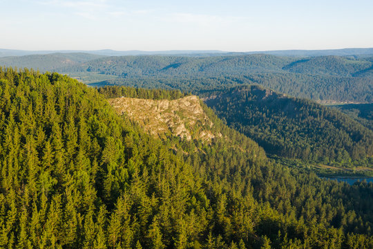 Bare rock among green mountains covered by pine trees forest in Ural, Bashkortostan, Russia