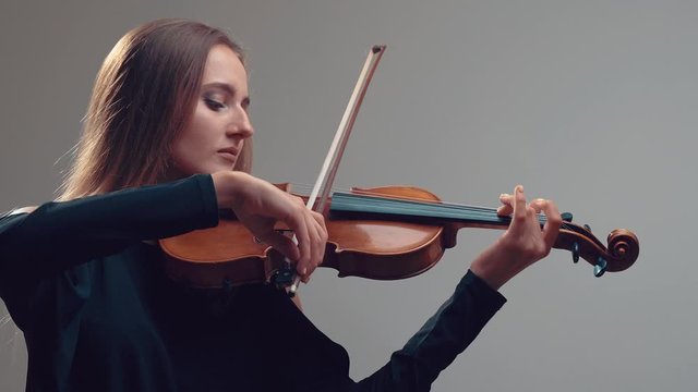 Girl violin playing at studio. Woman is practicing playing musical instrument