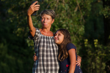 Grandmother with granddaugther making selfi outdoor at evening 