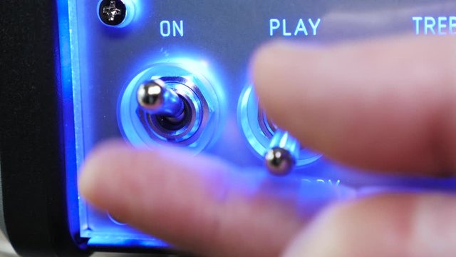 Rock musician starts to play electric guitar, takes the guitar, puts cables in,  turns on the amplifier, adjusts the sound and plays