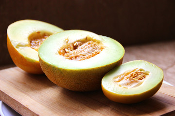 Three melons lined up on the cutting board