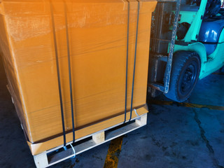 Worker driving forklift loading and unloading shipment carton boxes and goods on wooden pallet from container truck to warehouse cargo storage in logistics and transportation industrial 