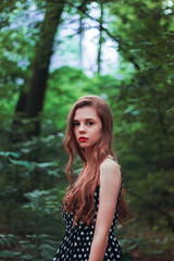 Portrait of a bright girl with long hair in nature. Expressive eyes and red lips