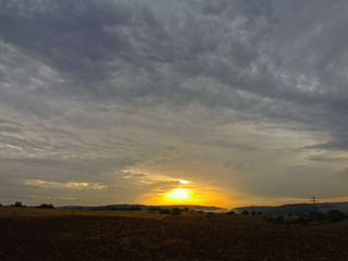 Fototapeta na wymiar Sonnenuntergang am Horizont mit dunklen Wolken am weiten Himmel