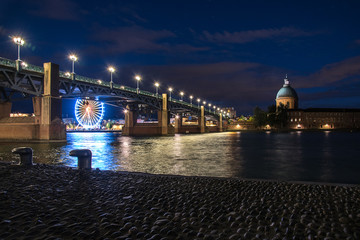 belle vue de nuit sur un pont et une église illuminés au bord d'un fleuve en ville 