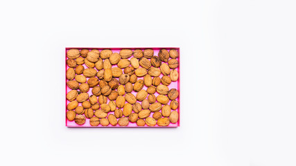 Natural walnuts stacked in a pink box. Everything is arranged on a bright table. Flat, top view, no people.
