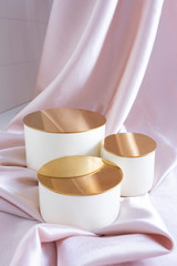 three beige podium topper with a gold top on a satin background with folds. Luxurious showcase for advertising and promotion..