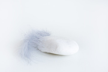 smooth white stone and gray feather on a white background. Luxurious showcase for advertising and promotion..