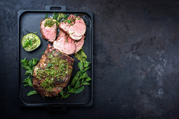 Traditional English barbecue lamb roast sliced with mint leaf and sauce offered as top view in a...