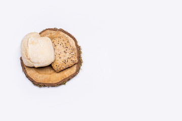 Still life of organic products. Organic bread placed on a round piece of wood. Everything is placed on a bright table. Flat, top view, no people.