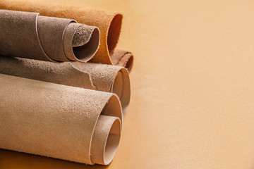 Rolls of natural brown and beige leather. Materials for leather craft. On yellow background