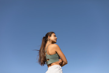 Fototapeta na wymiar Confident sporty young fit woman. Fitness motivation and success concept. Female motivated runner isolated on blue clear sky.
