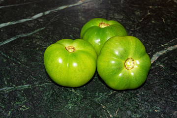 Green tomatoes over marble texture background.