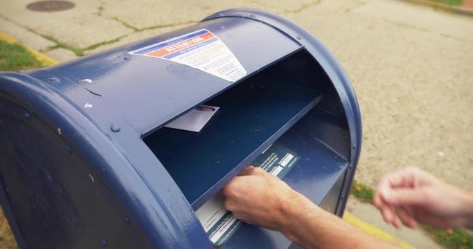A man puts an absentee mail-in ballot in the mailbox.	