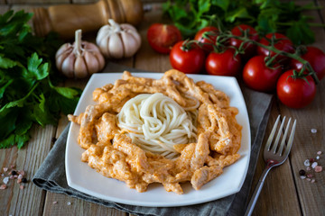 Beef Stroganoff with macaroni on a white plate on a wooden table