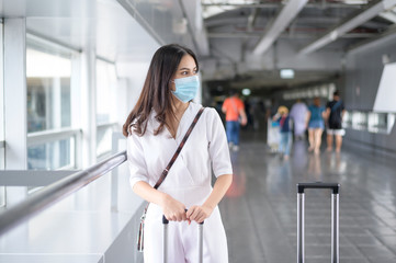 A traveller woman is wearing protective mask in International airport, travel under Covid-19 pandemic, safety travels, social distancing protocol, New normal travel concept