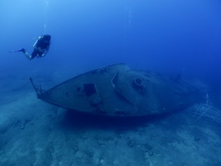 scuba divers exploring shipwreck scenery underwater ship wreck deep blue water ocean scenery of metal underwater and fish around