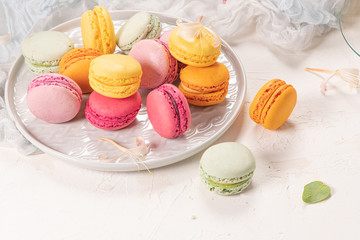 Colorful french macaroon cakes. Macaroons with jasmine flowers on white table background. Selective focus