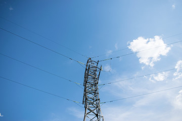 power line with wires in different directions on the background of a blue sky with clouds.