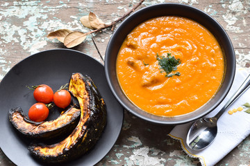 creme de abóbora e abóbora assada com tomates em mesa rústica