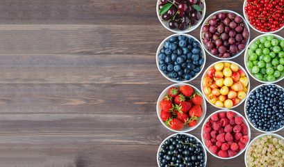 A set of berries in the round plates. Brown wooden background. Copy space. Flat top view