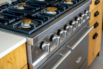 Gas stove with and embedded electric oven at brand new modern wooden kitchen. Close up photo