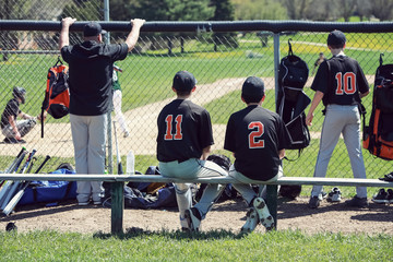 Teenagers in dugout behind chainlink fencing, shallow focus - obrazy, fototapety, plakaty