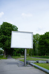 A large metal billboard on the street with a place for your advertising, a billboard on a background of trees