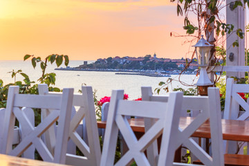 Seaside landscape at sunrise - the cafe on the embankment view of the Old Town of Nesebar, on the Black Sea coast of Bulgaria
