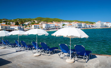 Fototapeta na wymiar Umbrellas and beach chairs on beach in idyllic Greek island Spetses
