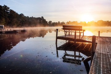 Fog over lake at sunrise from a dock during autumn