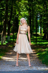 Young beautiful blonde girl in beige dress, summer park outdoor