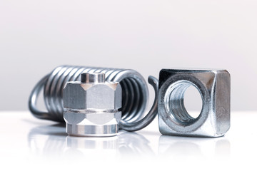 Metal nuts and helical spring  on white background
