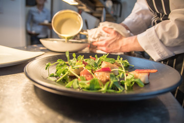 Chefs preparing fish main course dish 